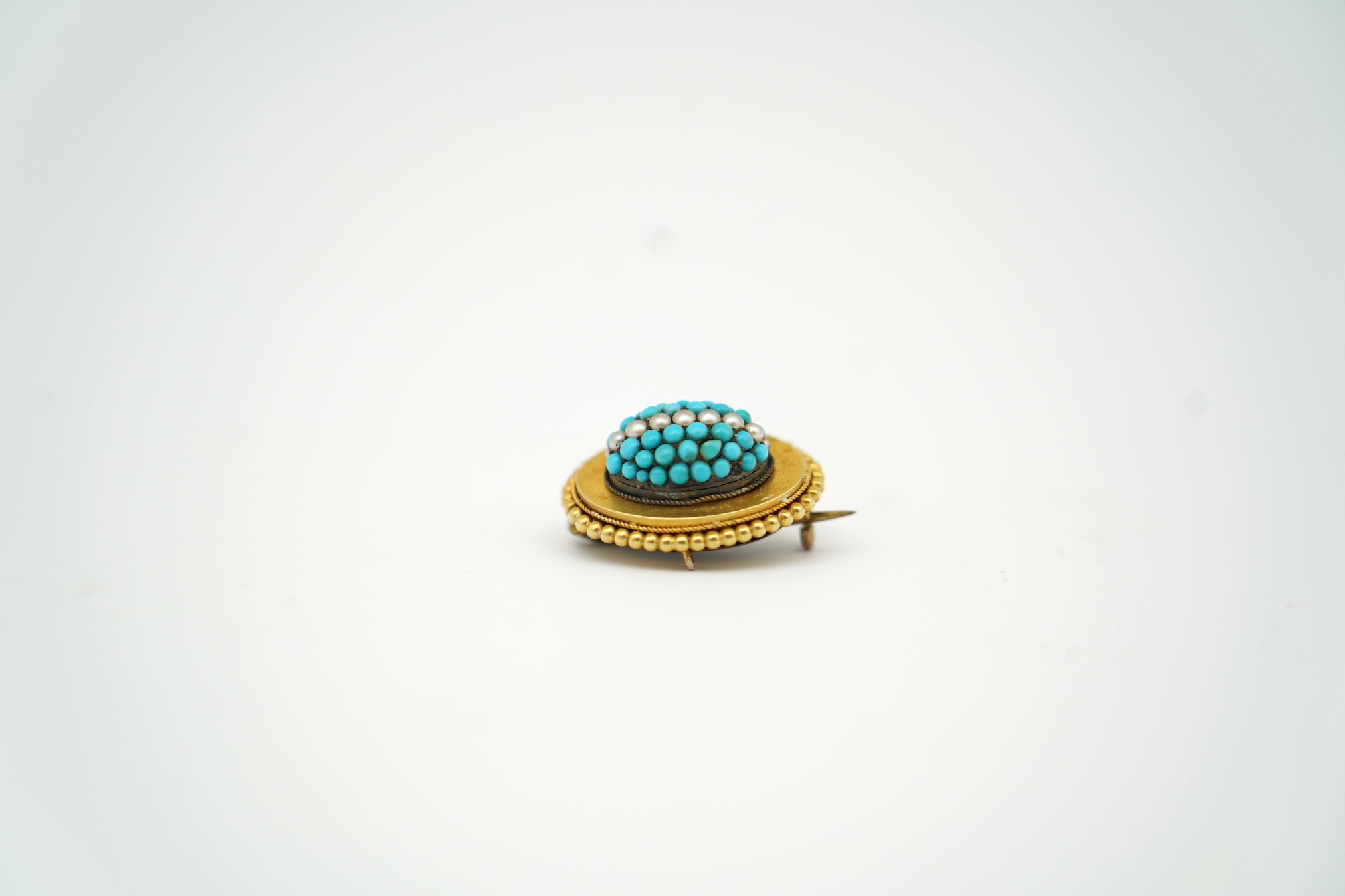 A Victorian yellow metal, turquoise and seed pearl set domed cluster mourning brooch, with plaited hair verso, 22mm. Condition - poor to fair